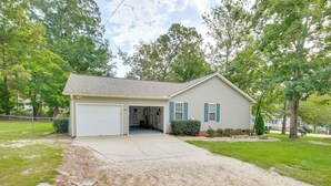 A single-story house with a garage, a front yard with a gravel driveway, and a small front garden. - Chapin Home Near Boat Launch & Lake Murray! (Chapin)