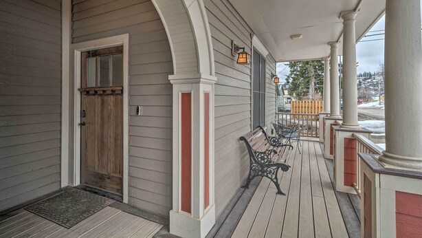 A covered porch with a wooden door, a bench, and a railing. - Updated Townhome w/ Hot Tub - Walk to Downtown! (Red Lodge)