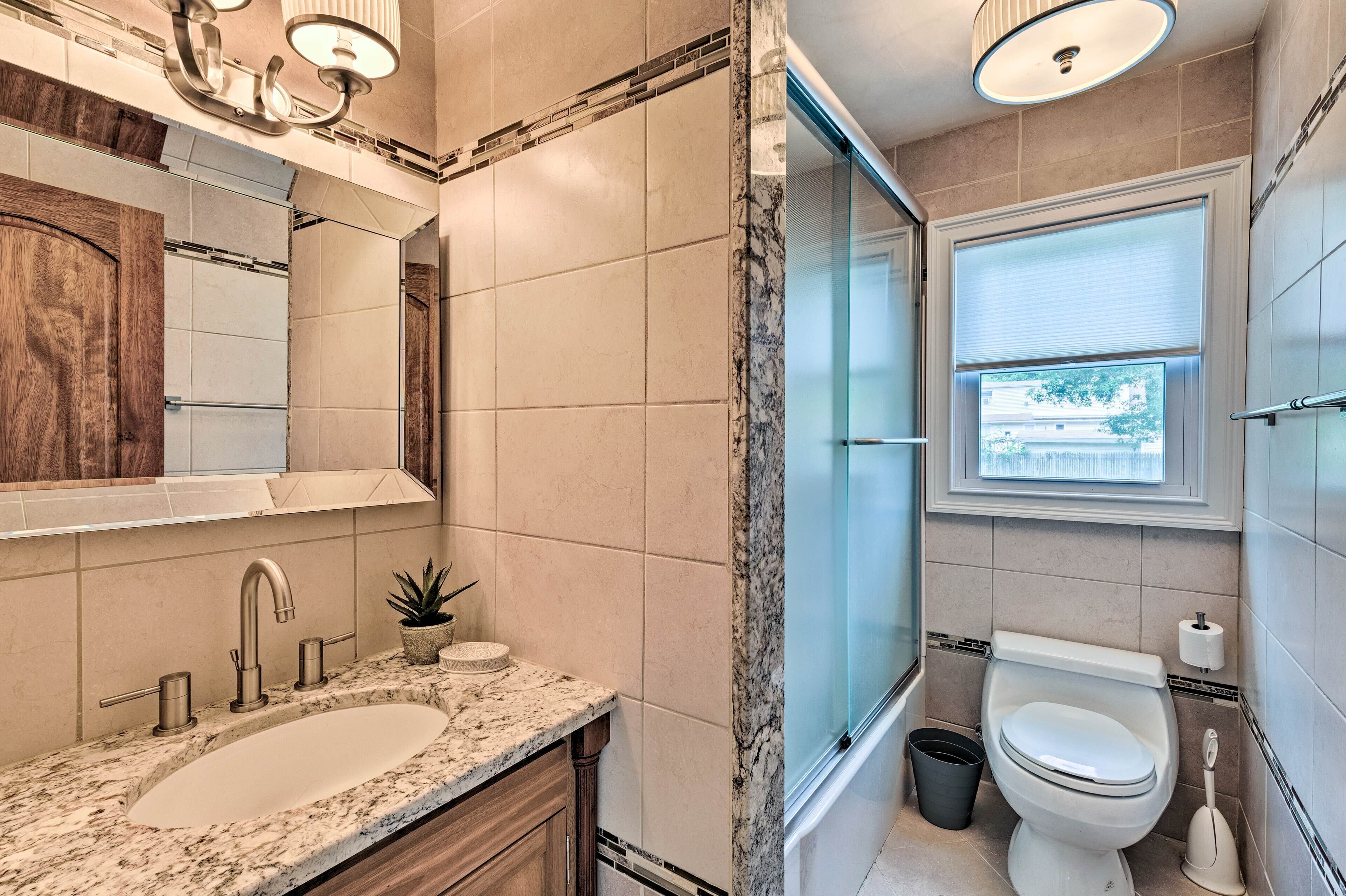 Un baño moderno con lavamanos, espejo y retrete.