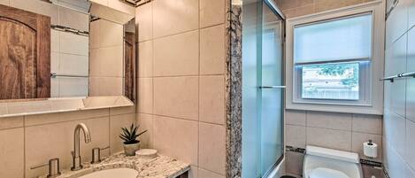 Un baño moderno con lavamanos, espejo y retrete.