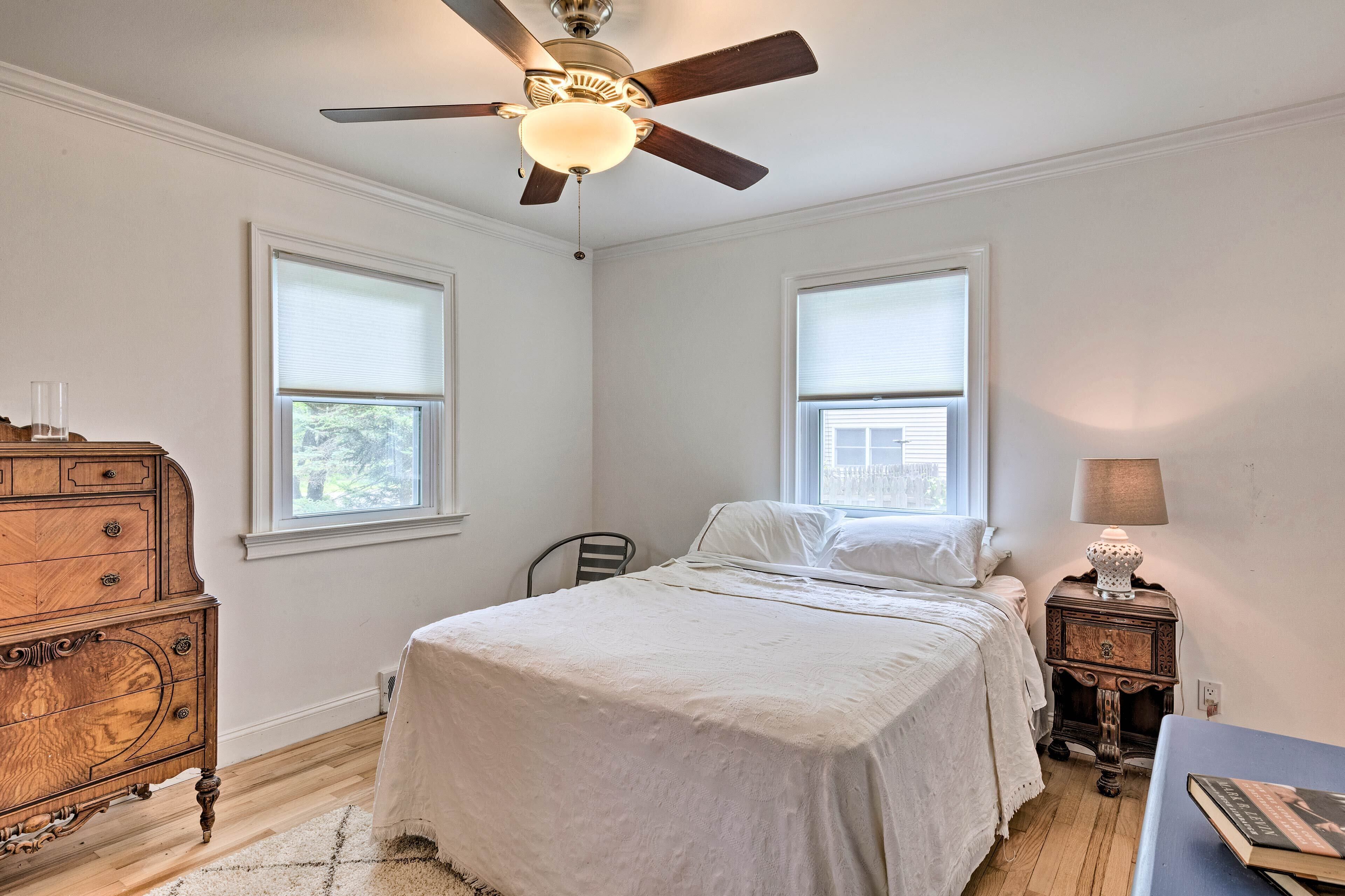 A bedroom with a bed, dresser, nightstand, lamp, and ceiling fan.