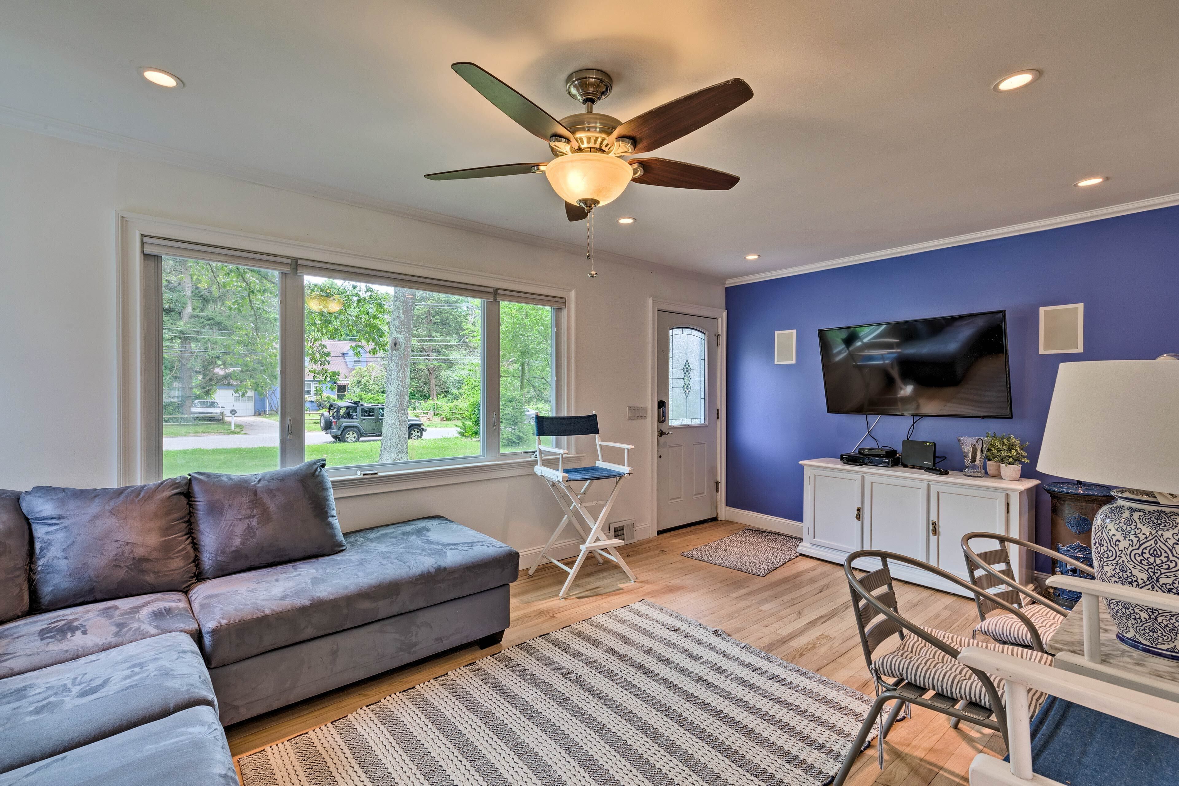 A living room with a gray sofa, a ceiling fan, a television, and a cabinet.
