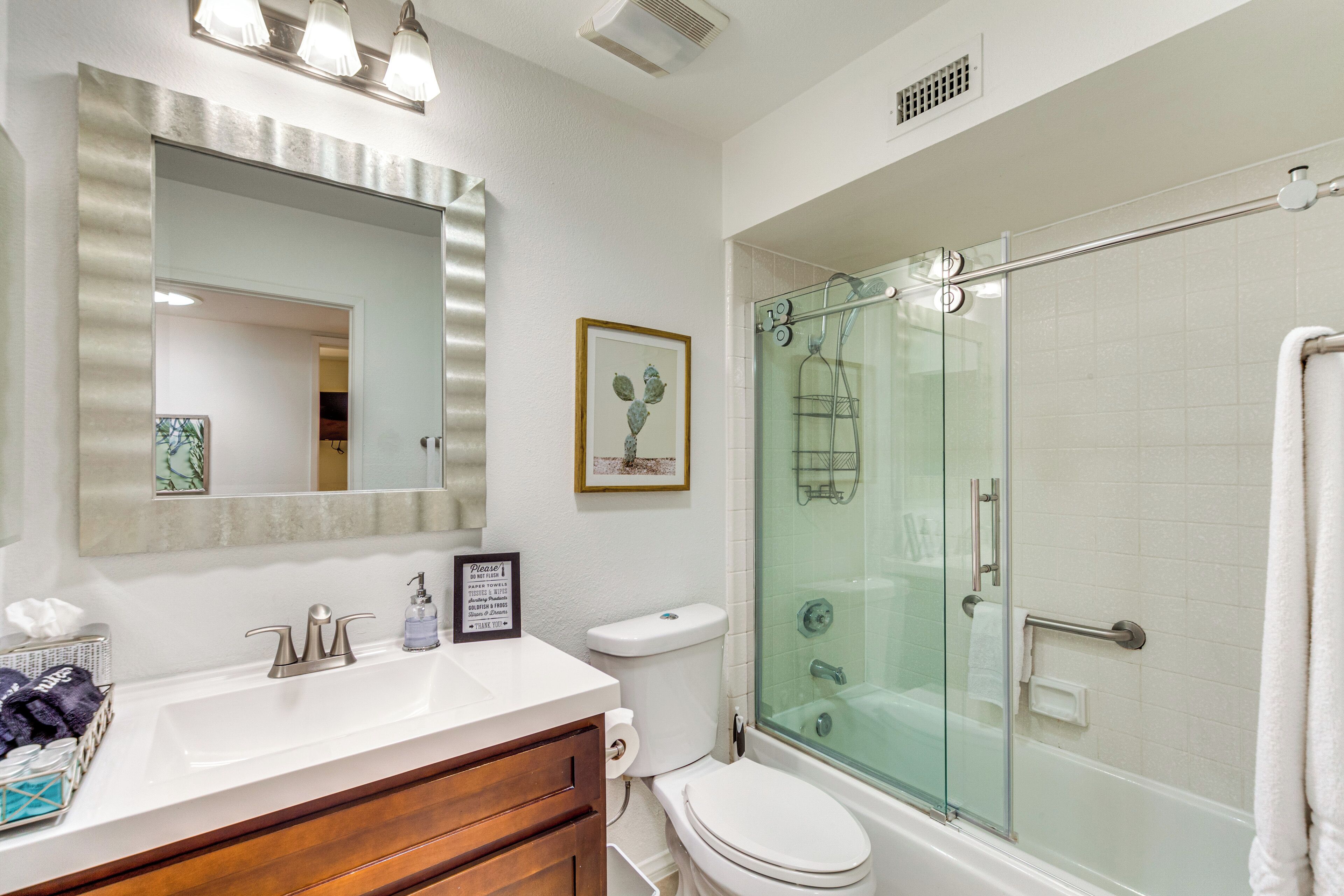 A modern bathroom with a glass-enclosed shower, a vanity with a mirror, and a toilet.