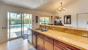 A modern kitchen with granite countertops, a stainless steel sink, and a large window overlooking a pool. - Private Pool & Putting Green: Palm Springs Home! (Palm Springs)