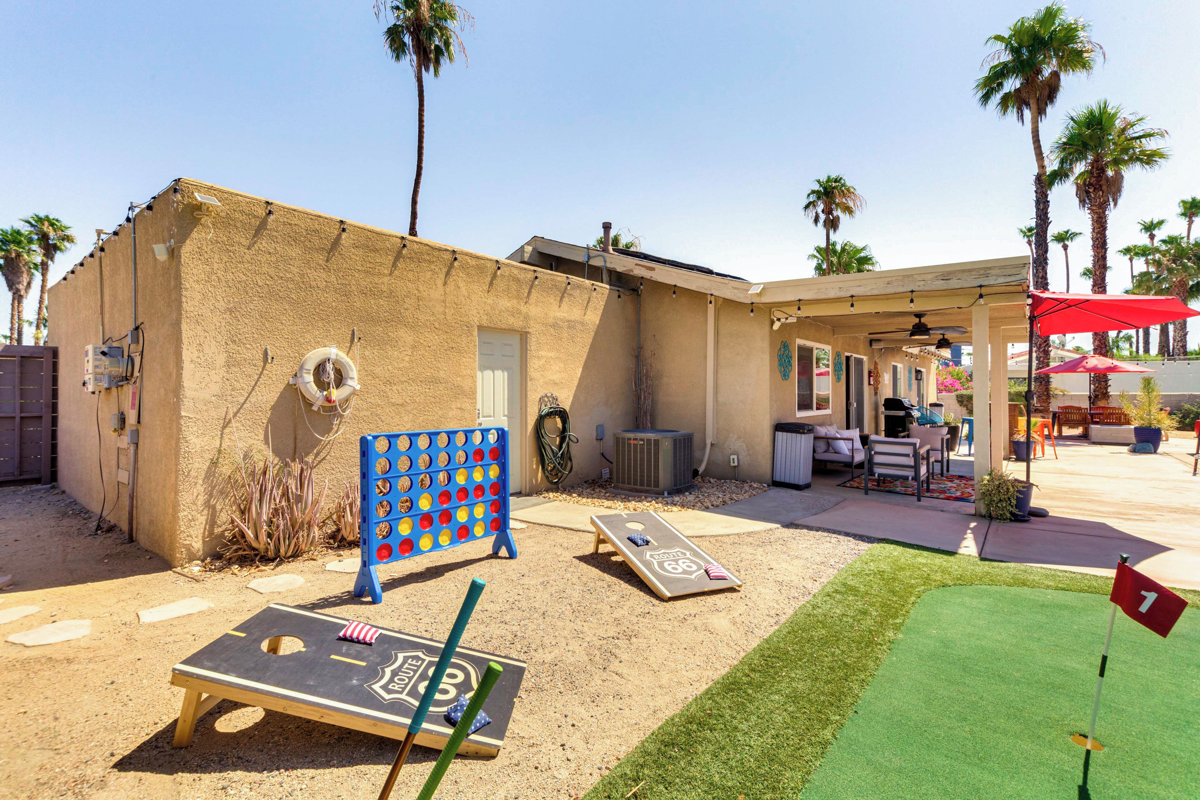 A backyard with a pool table, a bocce ball court, and a putting green.