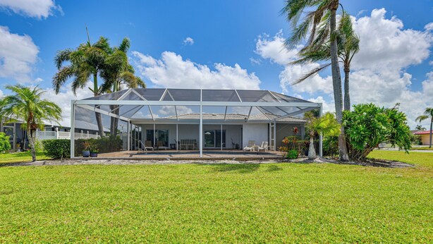 A modern house with a covered patio, surrounded by a well-maintained lawn and palm trees. - Pool, Lake & Sunset Views: Home in Sarasota (Sarasota)