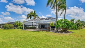 A modern house with a large glass facade, surrounded by a well-maintained lawn and palm trees. - Pool, Lake & Sunset Views: Home in Sarasota (Sarasota)