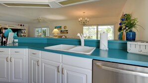 A kitchen with white cabinets, a teal countertop, a white sink, a toaster, and a ceiling fan. - Pool, Lake & Sunset Views: Home in Sarasota (Sarasota)