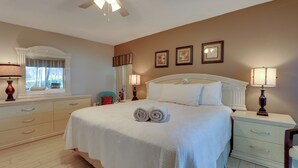 A neatly arranged bedroom with a large bed, bedside lamps, a window with curtains, and a ceiling fan. - Pool, Lake & Sunset Views: Home in Sarasota (Sarasota)