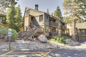 A multi-story building with a stone facade, balconies, and a staircase leading to the entrance.