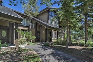 A two-story building with a covered porch, a driveway, and surrounding trees.