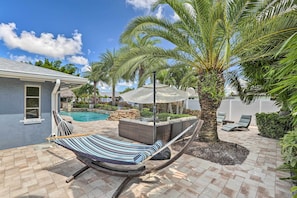 Eine Hängematte in einem Garten mit Pool, Palmen und Gartenmöbeln.