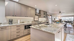 A modern kitchen with a large island, built-in appliances, and a skylight. - Ideally Located San Francisco Bay Home w/ Sunroom! (Alameda)