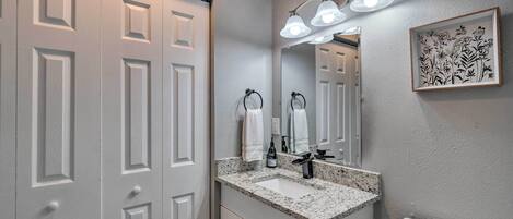 Un baño con una puerta blanca, un lavabo con grifo, un inodoro y una lámpara fijada a la pared.