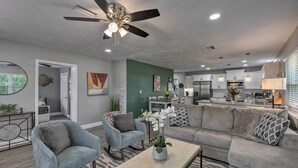 A modern living room with a sofa, chairs, and a coffee table. There is a ceiling fan, a kitchen in the background, and a dining area. - Bright Venice Getaway < 1 Mi to Historic Dtwn (Venice)
