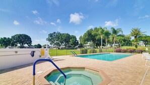 Ein Poolbereich mit Whirlpool, Liegestühlen und einem umzäunten Garten.