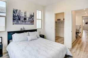 A bedroom with a bed, a nightstand, a wall-mounted bicycle, a framed picture, and a door leading to another room. - 4 Mi to Beach! San Juan Capistrano Home w/ Patio (San Juan Capistrano)