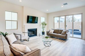 A spacious living room with a fireplace, a television mounted on the wall, and a large sliding glass door leading to an outdoor area. - 4 Mi to Beach! San Juan Capistrano Home w/ Patio (San Juan Capistrano)
