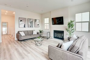 Ein modernes Wohnzimmer mit Kamin, einer Couch, einem Couchtisch und abstrakter Wandkunst.