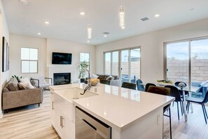 A modern kitchen with a large island, a dining area with a glass table, and a living room with a sofa and TV. - 4 Mi to Beach! San Juan Capistrano Home w/ Patio (San Juan Capistrano)