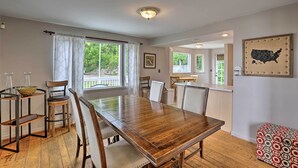 A dining area with a wooden table, chairs, and a bench. There are windows with curtains, a wall-mounted map, and a ceiling light. - Queen City Home w/ Ohio River View - 3 Mi to Dtwn! (Cincinnati)