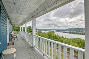 Een overdekte veranda met uitzicht op een rivier en heuvels.
