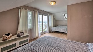 A bedroom with a large bed, a bedside table, a window with curtains, and a balcony. - Queen City Home w/ Ohio River View - 3 Mi to Dtwn! (Cincinnati)