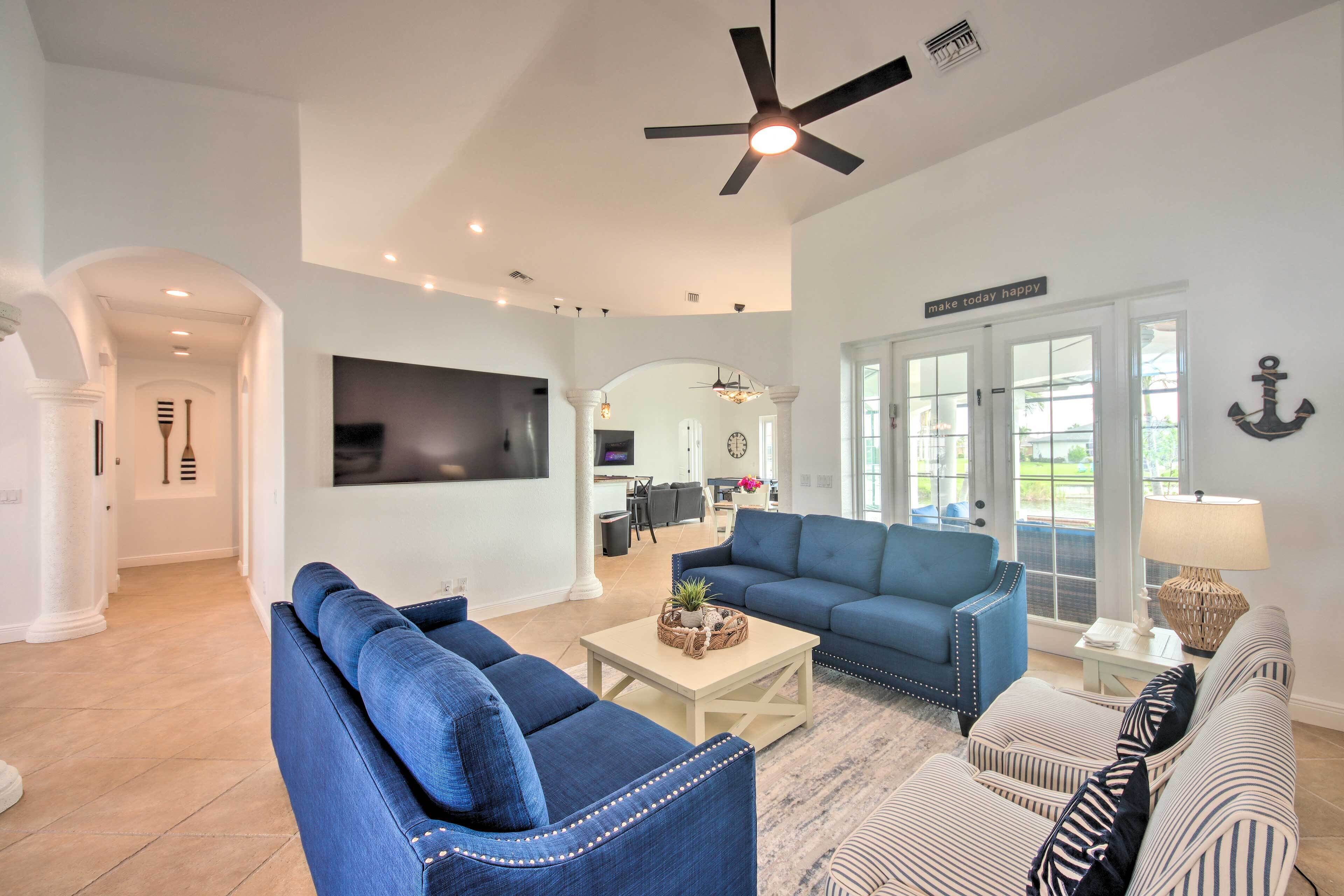 A spacious living room with a large TV, a ceiling fan, and a dining area with a table and chairs.