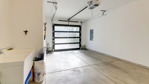 A garage with a concrete floor, a white wall, and a garage door. - Scenic Depoe Bay Townhome w/ Deck < 1 Mi to Parks! (Depoe Bay)