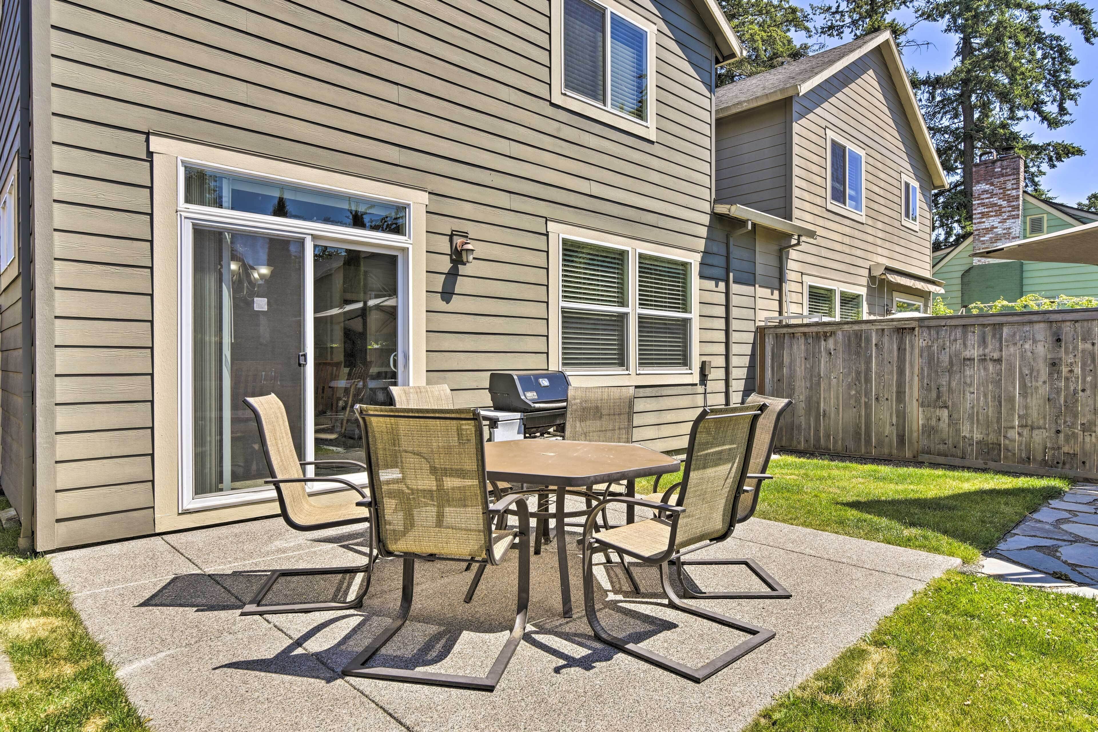 A patio with a table and chairs, a sliding glass door, and a wooden fence.