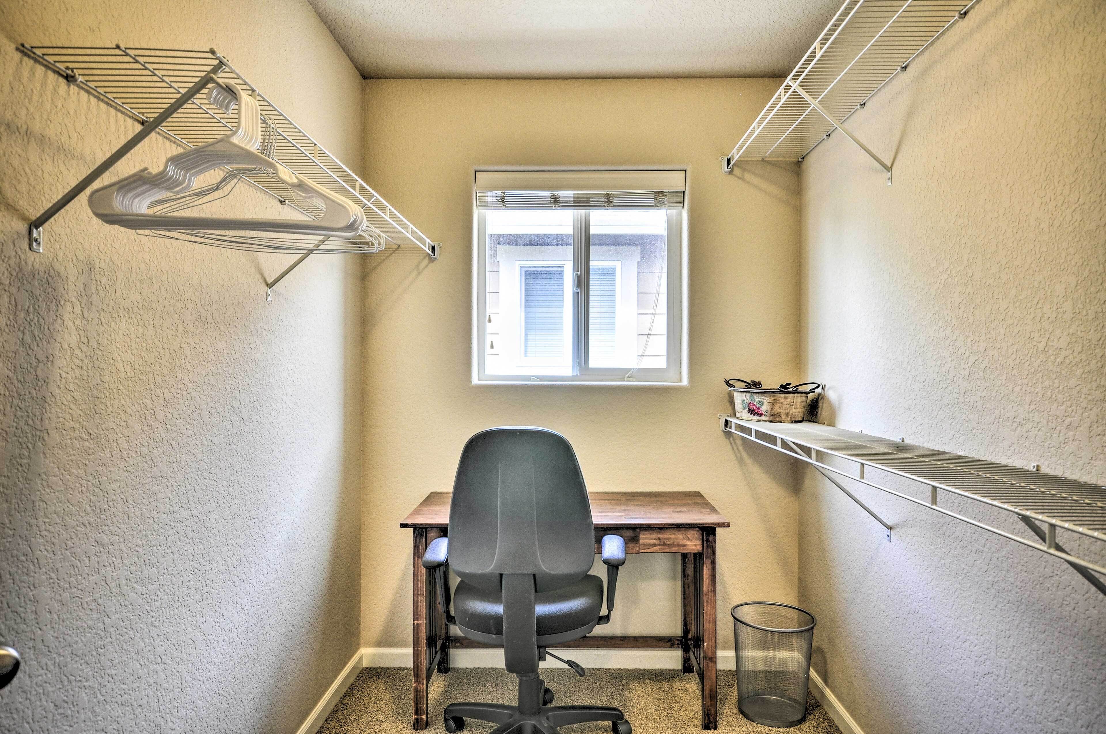 Un espacio de oficina pequeño con escritorio, silla de oficina, ventana y estanterías empotradas.