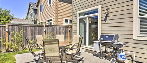 A patio with a table and chairs, a grill, and a propane tank.