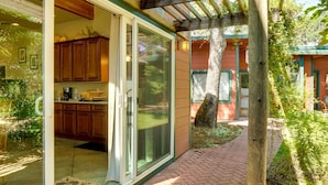 Une façade en bois avec une porte vitrée donnant sur un espace cuisine.
