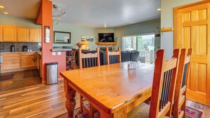 A spacious kitchen with wooden cabinets, a dining table, and a TV above it. - Cozy Condo w/ Views, 3 Mi to Winter Park Resort! (Winter Park)