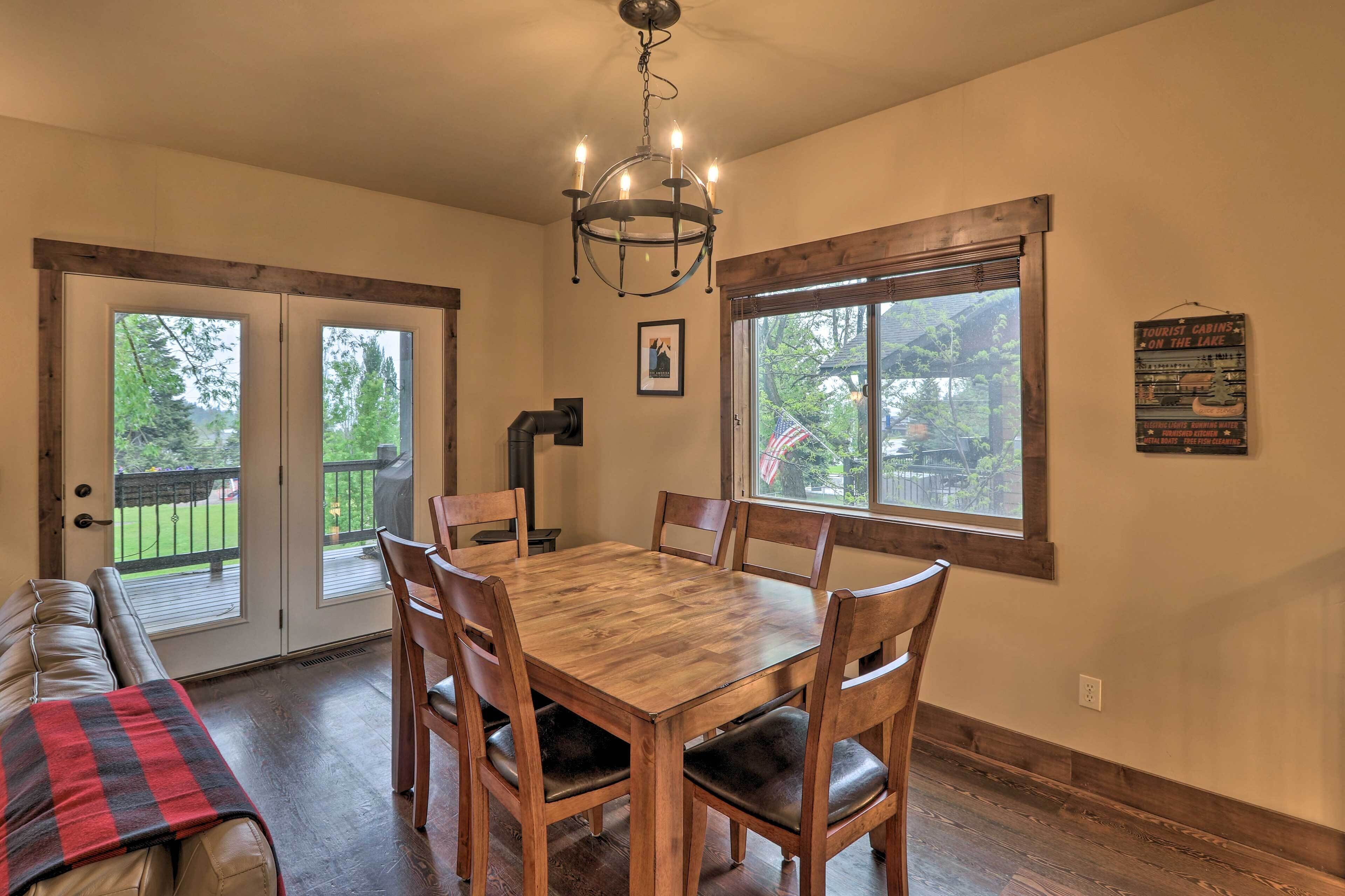 A dining area with a wooden table and chairs, a bench with a plaid blanket, and a chandelier.
