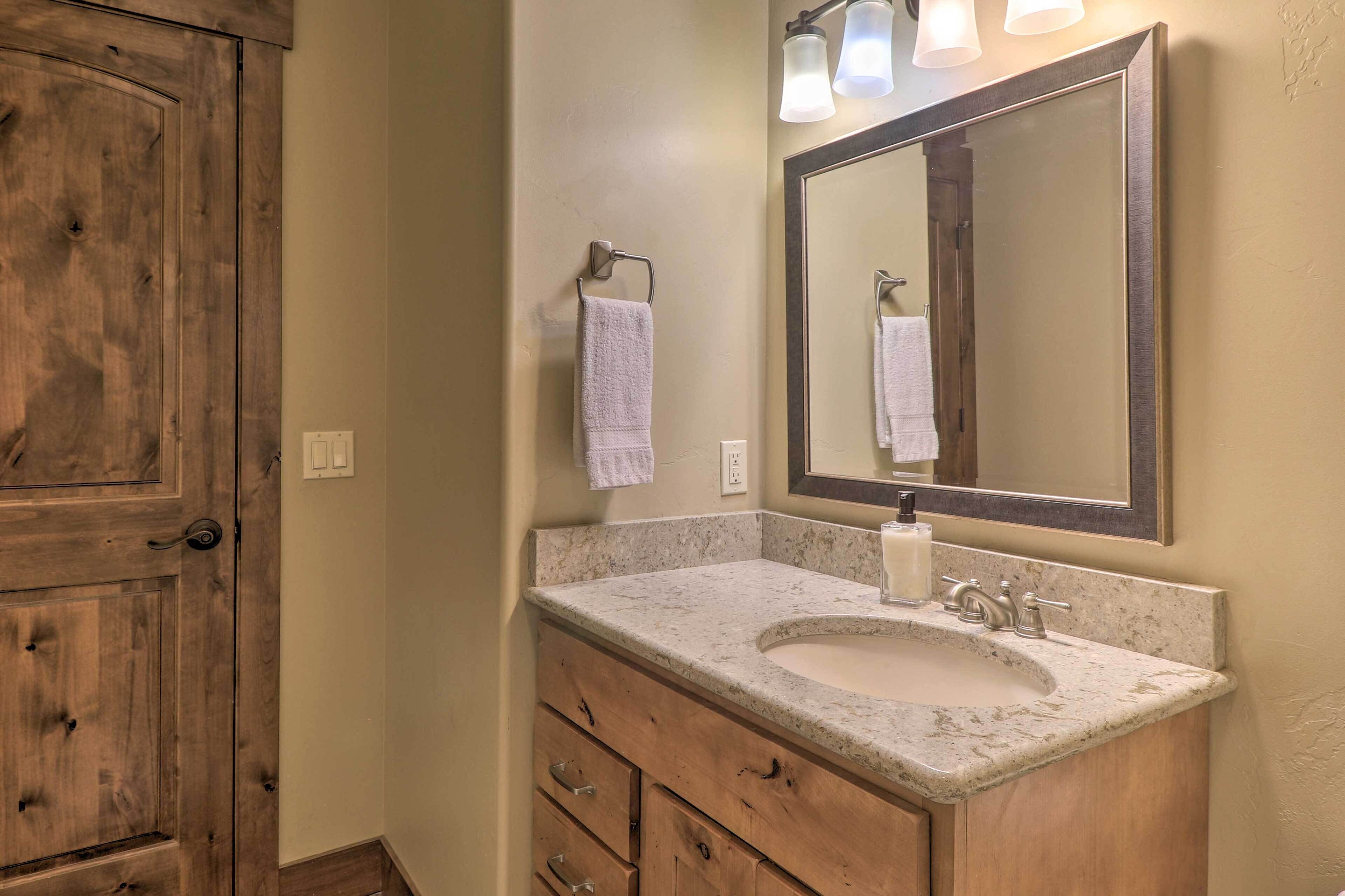 A bathroom with a wooden door, a marble sink, a large mirror, and a towel hanging on the wall.