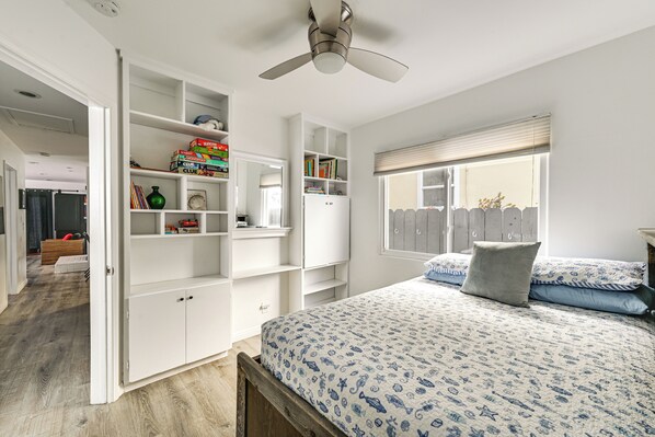 Quarto com cama, guarda-roupa e ventoinha no teto.