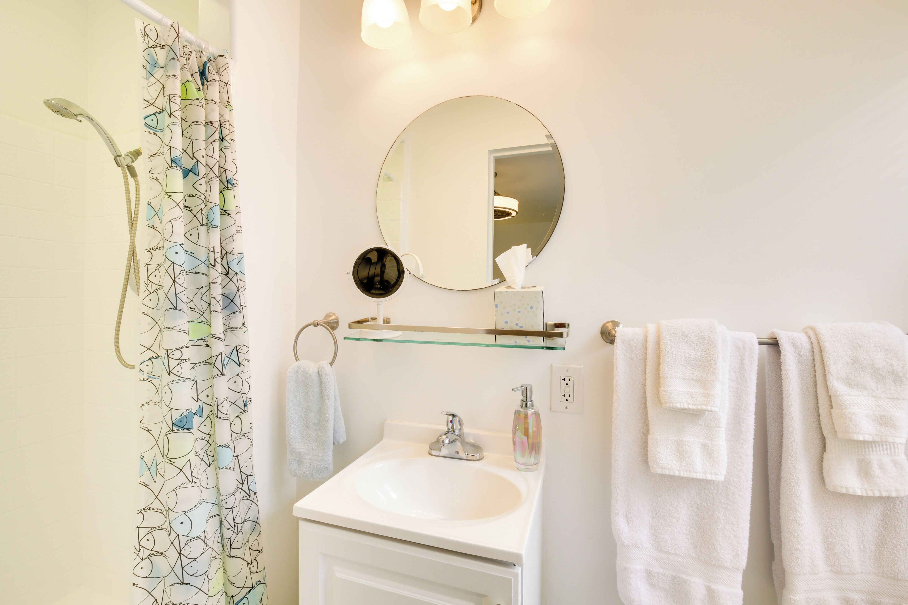 A bathroom with a shower, a sink, a mirror, and towels.