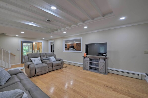 A living room with a grey sofa, a television, and a wooden floor. - Coastal Edgewater Home w/ Private Hot Tub! (Edgewater)