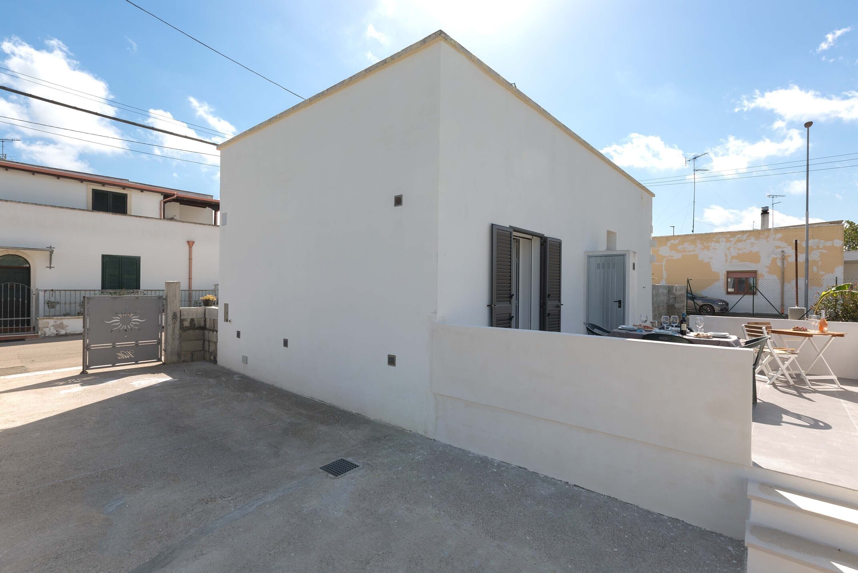 A white building with a small balcony and a gate.