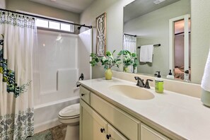 A bathroom with a bathtub, toilet, sink, and a mirror. - Fayetteville Home Near University of Arkansas! (Fayetteville)