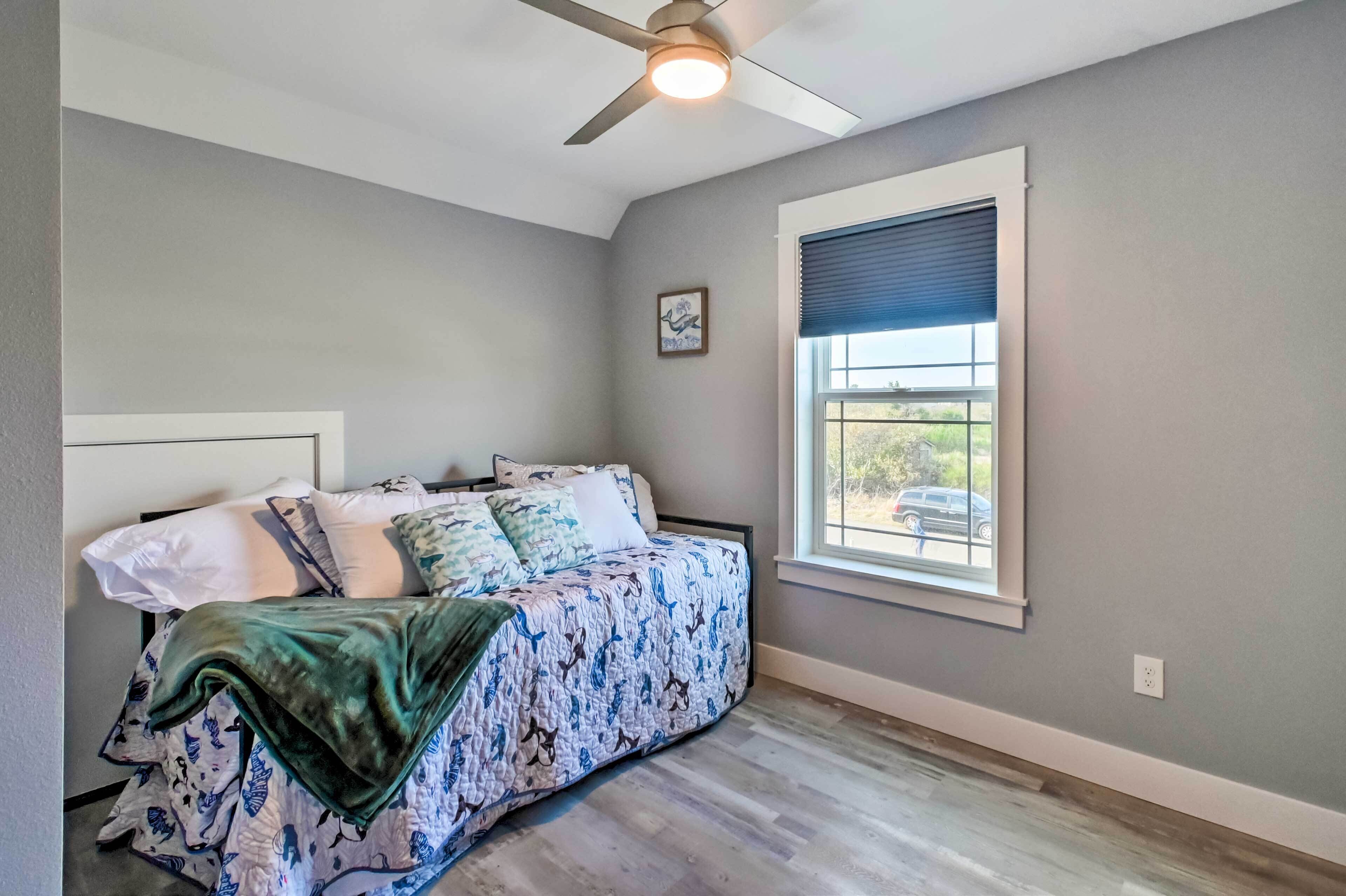 A bedroom with a bed, a ceiling fan, a window with blinds, and a small picture on the wall.