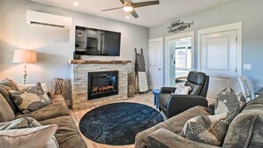 A living room with a fireplace, a ceiling fan, a flat-screen TV, and a comfortable seating area with a round rug. - Ocean Shores Getaway w/ Fireplace & Hot Tub! (Ocean Shores)