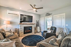 A living room with a fireplace, a ceiling fan, a flat-screen TV, and a comfortable seating area with a round rug. - Ocean Shores Getaway w/ Fireplace & Hot Tub! (Ocean Shores)