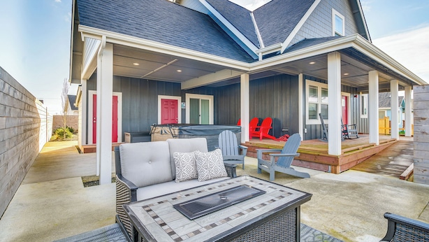 A covered patio area with outdoor furniture, a hot tub, and a play area with red chairs. - Ocean Shores Getaway w/ Fireplace & Hot Tub! (Ocean Shores)