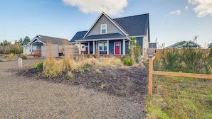 A residential house with a grey roof, a front porch, and a gravel driveway. - Ocean Shores Getaway w/ Fireplace & Hot Tub! (Ocean Shores)