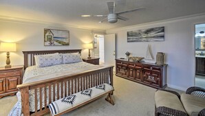Une chambre à coucher avec un lit en bois, un banc, une commode et un ventilateur de plafond.