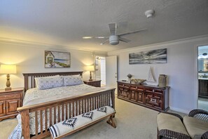 Un dormitorio con cama de madera, un banco, cómoda y ventilador de techo.