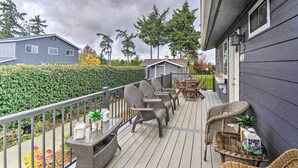 Une terrasse en bois avec des meubles en osier, une petite table et une rambarde.