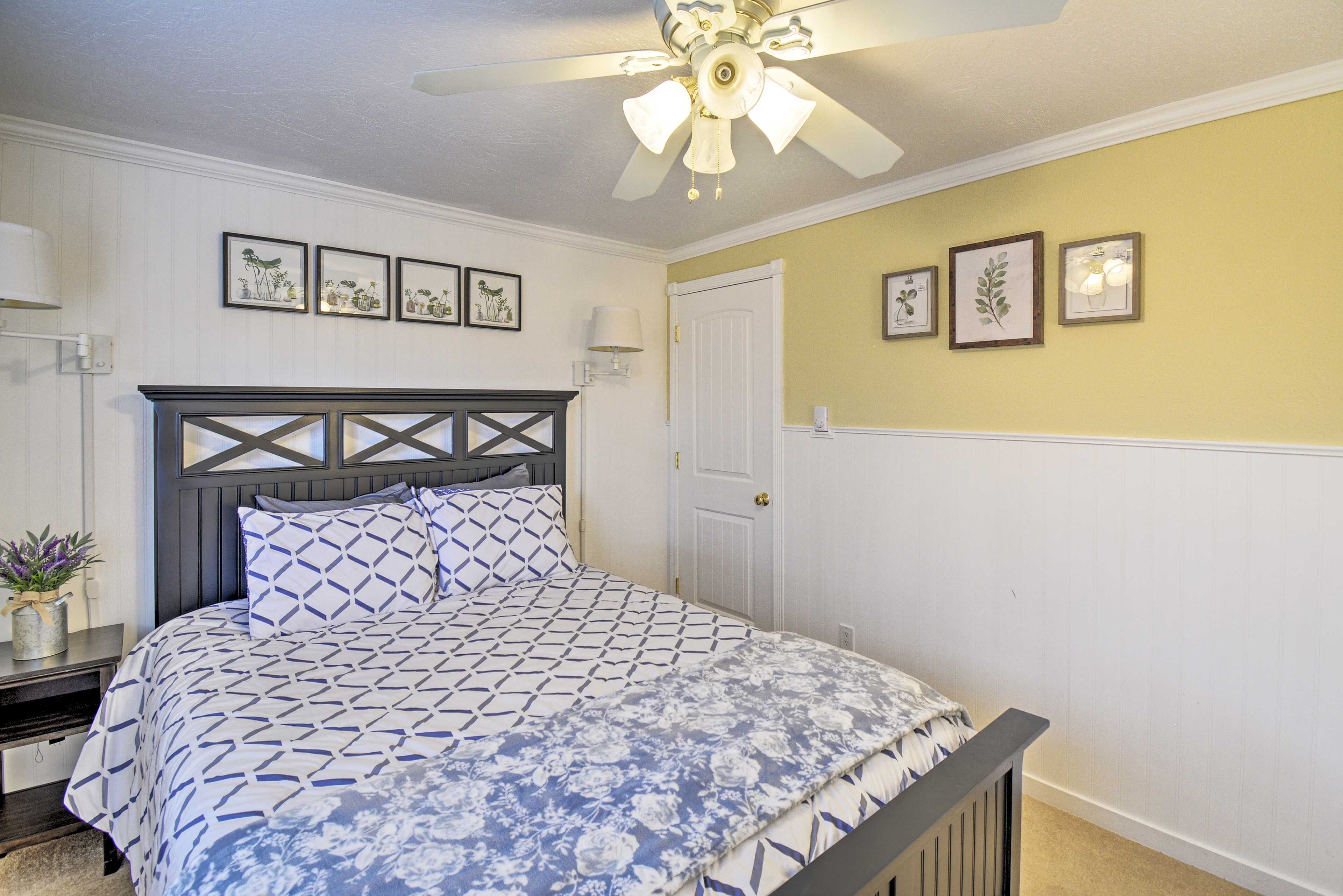 A bedroom with a bed, a ceiling fan, and wall-mounted artwork.